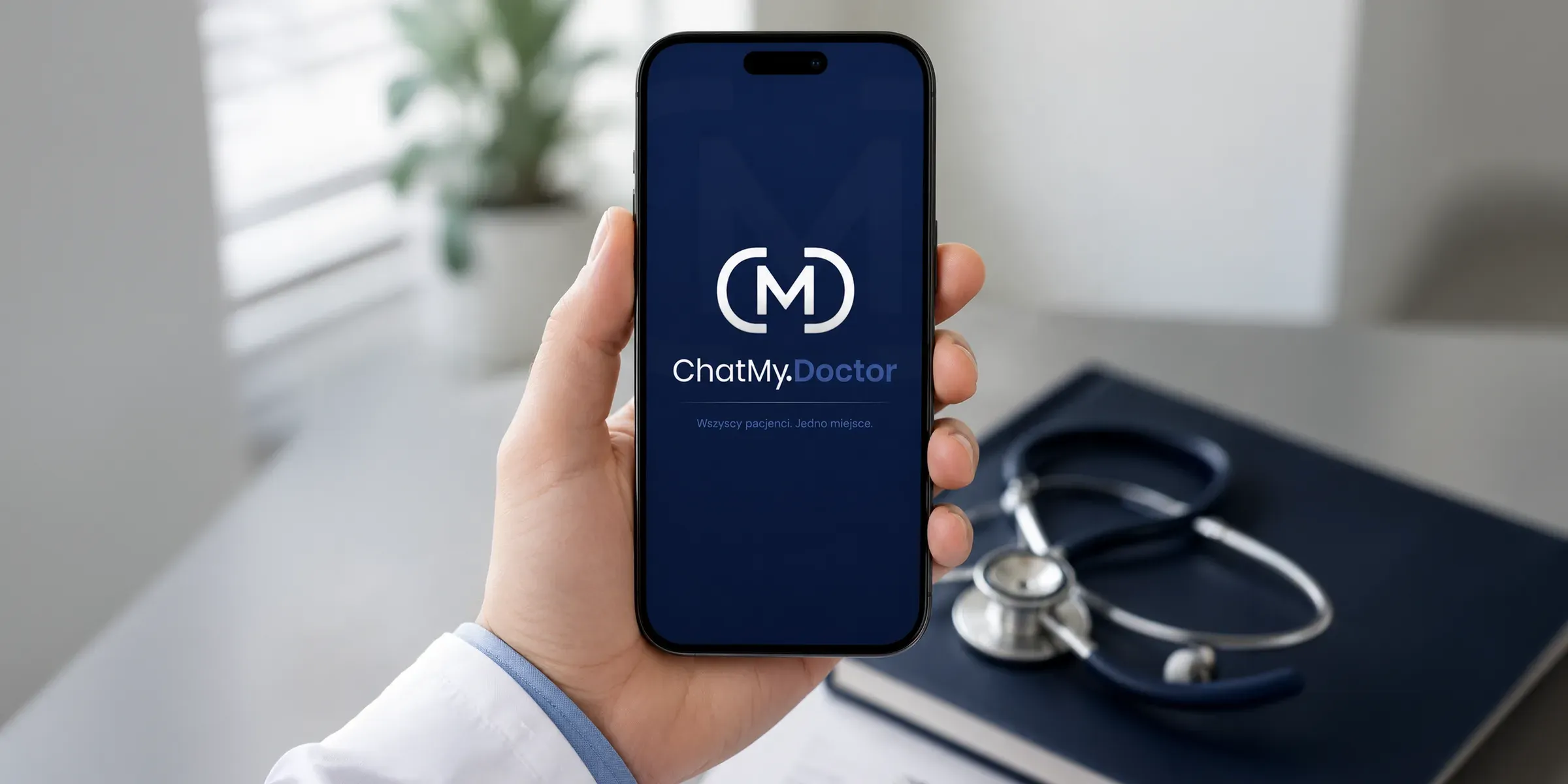 Dłoń lekarza w białym fartuchu trzyma smartfon z ekranem powitalnym ChatMy.Doctor: monogram „CM”, logotyp i hasło „Wszyscy pacjenci. Jedno miejsce.” na granatowym tle. W tle rozmyte biurko ze stetoskopem na granatowym notesie i roślina przy oknie.